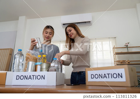 Donation and two woman volunteer asian of happy packing food in box at home. Charity 113811326