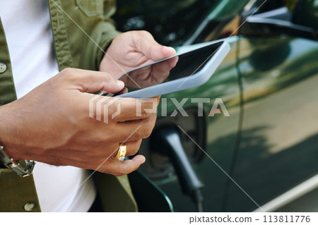 Closeup image of ev owner checking battery level via app Closeup image of ev owner checking battery level via app 113811776