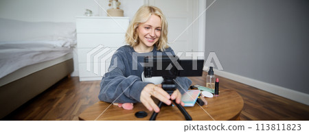 Portrait of young teenage girl in her room, recording a vlog, daily lifestyle video for social media, internet influencer advertising product online, talking to the camera, sitting on the floor Portrait of young teenage girl in her room, recording a vlog, daily lifestyle video for social media, internet influencer advertising product online, talking to the camera, sitting on the floor 113811823