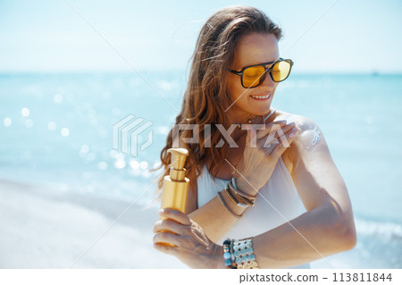 smiling stylish female on seacoast with sunscreen smiling stylish female on seacoast with sunscreen 113811844