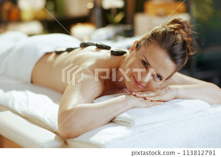 woman having hot stone massage and laying on massage table woman having hot stone massage and laying on massage table 113812791