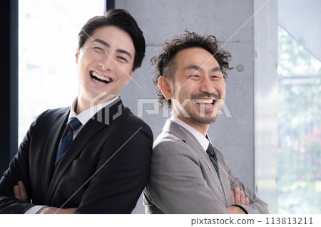 Businessmen in suits standing back to back with their arms folded, looking up. Image of looking towards goals and the future. 113813211