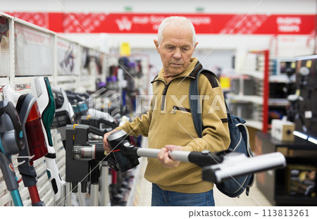 Senor man pensioner buying Upright Vacuum Cleaner in showroom of electrical appliance store Senor man pensioner buying Upright Vacuum Cleaner in showroom of electrical appliance store 113813261