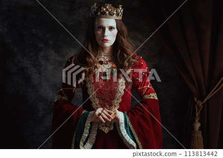 medieval queen in red dress with white makeup and crown 113813442