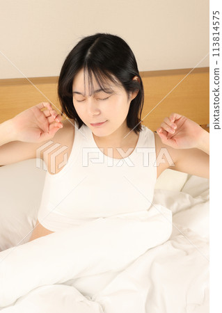 一個女人睡覺、醒來、在床上伸展身體 113814575