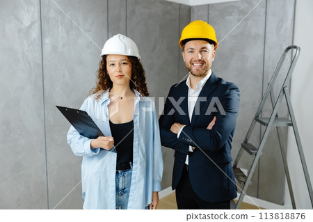 We've got the go ahead to renovate. Attractive young contractor and customer standing in room in helmet and looking at camera 113818876