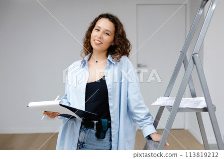 A young pretty girl designer keeps documents while standing at her workplace. Apartment renovation and design concept 113819212