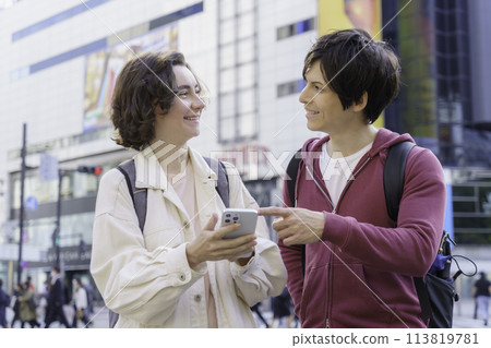 入境的外國夫婦在澀谷的十字路口一邊看著智慧型手機一邊聊天 入境的外國夫婦在澀谷的十字路口一邊看著智慧型手機一邊聊天 113819781