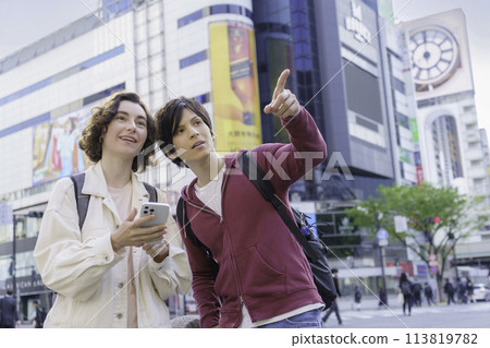 入境的外國夫婦在澀谷的十字路口一邊看著智慧型手機一邊聊天 113819782