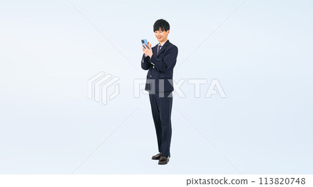 Full-body photo of a male student in uniform using a smartphone Full-body photo of a male student in uniform using a smartphone 113820748