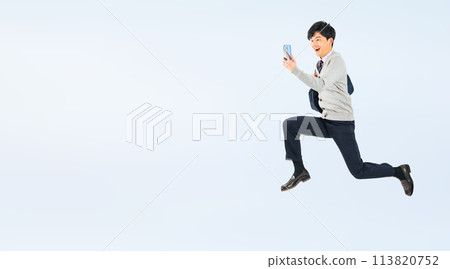 一名身穿制服的男學生看著智慧型手機跳躍的全身照片 一名身穿制服的男學生看著智慧型手機跳躍的全身照片 113820752