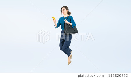 Full body photo of a white woman jumping while looking at her smartphone 113820832