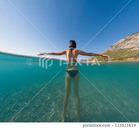 Woman on tropical vacation paradise on sea. Summer sea joy in Turkish seacoast, beaches along Lycian Way, Turkish Riviera. Asian female underwater and turquoise ocean around. Woman on tropical vacation paradise on sea. Summer sea joy in Turkish seacoast, beaches along Lycian Way, Turkish Riviera. Asian female underwater and turquoise ocean around. 113821619