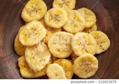 Dried organic bananas in wooden brown bowl top view. Crunchy dry fruit chips close up. 113821679