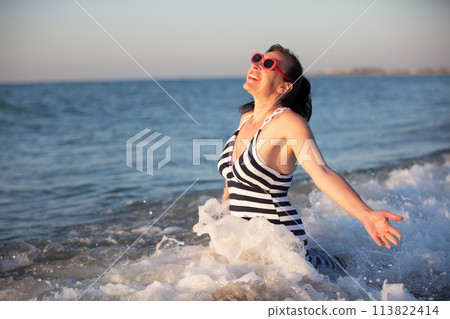 A beautiful old woman at sea. A beautiful middle-aged woman splashes sea water. A beautiful old woman at sea. A beautiful middle-aged woman splashes sea water. 113822414