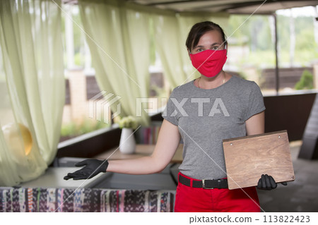 Happy waiter with protective mask holds the menu and invites to the restaurant. Happy waiter with protective mask holds the menu and invites to the restaurant. 113822423