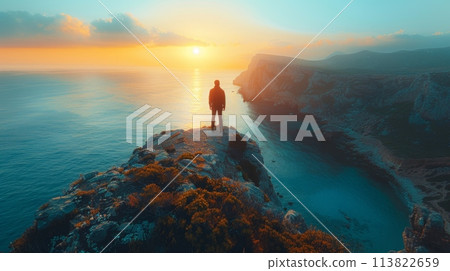 A very distant silhouette of a man on a high cliff above the ocean. Morning, summer. 113822659