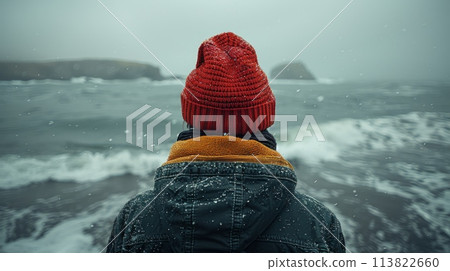 male tourist in a red hat, shot at a wide angle against the backdrop of the sea from the water level in winter in retro style. 113822660