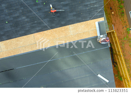 Roofing contractor to install new asphalt bitumen shingles on roof of home 113823351