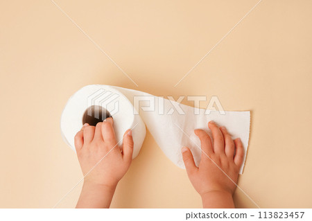 Roll of white toilet paper in child hands. beige background with copy space 113823457