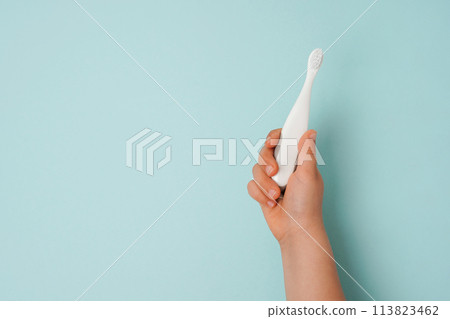 toothbrush in a child's hand on a blue background with space for text 113823462