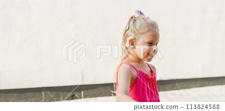 Banner child girl walks and have fun outdoor with cochlear implant on the head. Hearing aid and treatment concept. Copy space. Inclusion and people with disability Banner child girl walks and have fun outdoor with cochlear implant on the head. Hearing aid and treatment concept. Copy space. Inclusion and people with disability 113824588