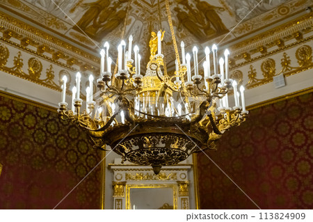 gold chandelier or luster with long electric candles on stucco ceiling with painting . two-tier chandelier lamp and luxury interior in Yusupov Palace. View from below. St. Petersburg, Russia 113824909