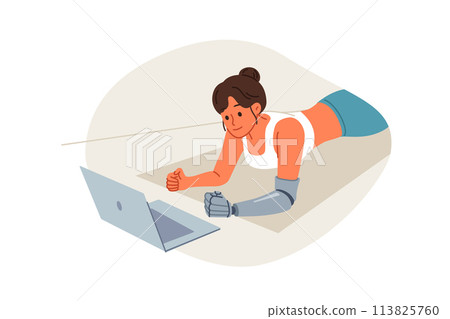 Sports woman with prosthetic arm trains at home and watches video lesson, lying on floor in plank 113825760