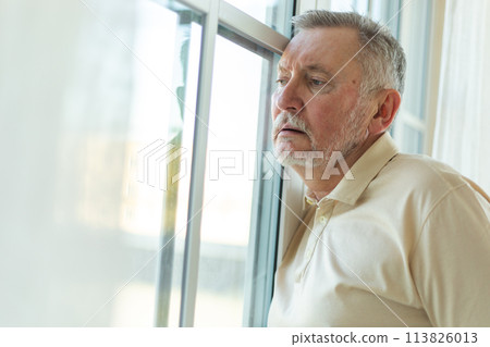 Sad tired lonely disappointed older senior man at home alone. Unhappy grandfather looking sadly outside window experiencing grief relative death bad news. Stressed elder man suffering from loneliness 113826013