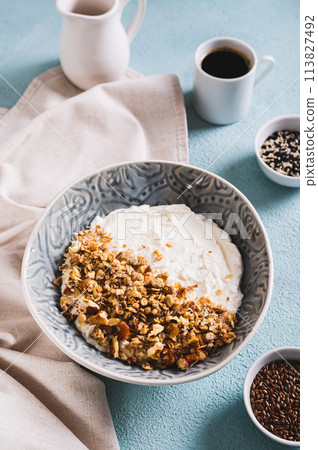 Granola with nuts in a bowl with classic yogurt for healthy eating on the table vertical view 113827492