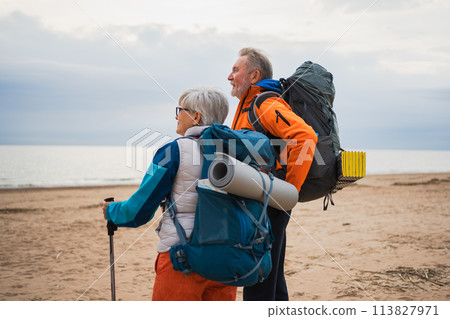 Hiking tourism adventure. Senior couple man woman enjoying outdoor recreation hiking on beach. Happy old people backpackers hikers enjoy walking hike trekking tourism active vacation beauty of nature Hiking tourism adventure. Senior couple man woman enjoying outdoor recreation hiking on beach. Happy old people backpackers hikers enjoy walking hike trekking tourism active vacation beauty of nature 113827971
