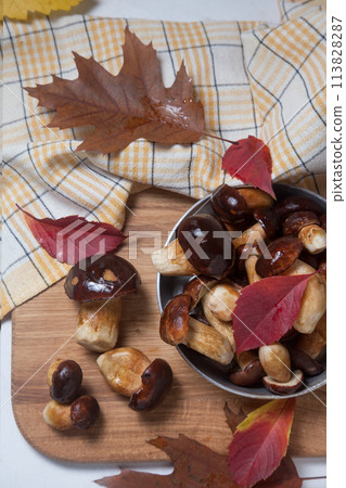 Several Imleria Badia or Boletus badius mushrooms commonly known as the bay bolete and vintage pan with mushrooms on wooden cutting board.. 113828287