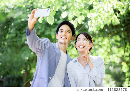 Couple taking a selfie in the park 113828578