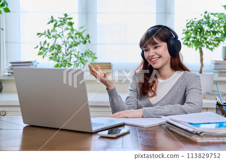 Girl teenage student in headphones having video chat online on computer 113829752