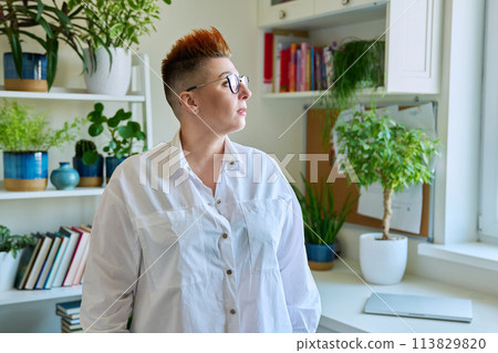 Profile portrait of serious middle-aged woman in glasses with red haircut 113829820