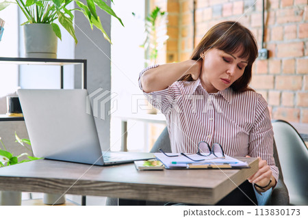 Mature tired worried tense woman at workplace experiencing neck and back pain 113830173