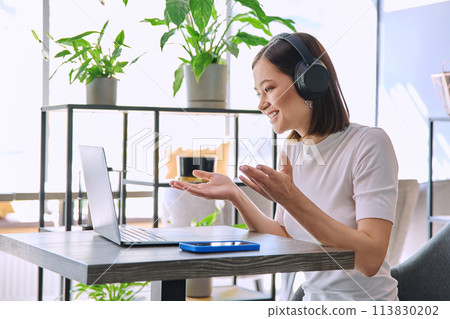 Young woman in headphones having work video chat conference call, using laptop in cafe Young woman in headphones having work video chat conference call, using laptop in cafe 113830202