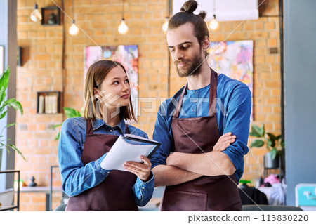 Business team, confident colleagues young man and woman in aprons with notebook 113830220