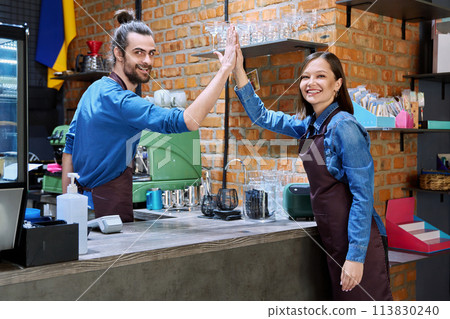Colleagues young cheerful man and woman in aprons give each other five, at workplace 113830240