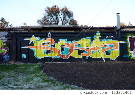 The old wall decorated with paint stains in the style of street art culture. Colorful background of full graffiti painting artwork with bright aerosol outlines on wall. Colored background texture 113831401