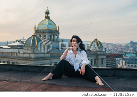 Attractive girl in white t-shirt and cardigan stands on the roof. 113831559