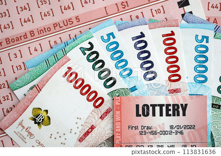 Red lottery ticket lies on pink gambling sheets with indonesian rupiah money bills. Lottery playing concept or gambling addiction in indonesia 113831636