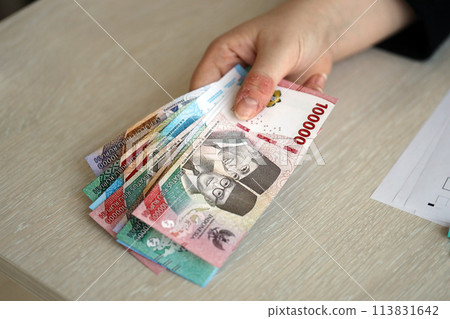 Female accountant hand give bunch of many indonesian rupiah money bills of new series close up Female accountant hand give bunch of many indonesian rupiah money bills of new series close up 113831642