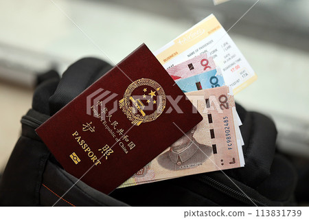Red passport of People Republic of China and chinese yuan money bills with airline tickets on backpack close up. PRC passport Red passport of People Republic of China and chinese yuan money bills with airline tickets on backpack close up. PRC passport 113831739
