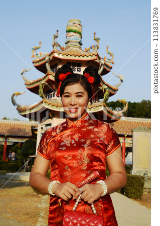 Portrait of a beautiful Asian woman in a red Chinese dresses pose and standing in front of Cinese pagoda inside a shrine. Portrait of a beautiful Asian woman in a red Chinese dresses pose and standing in front of Cinese pagoda inside a shrine. 113831769