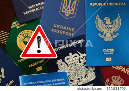 Many various passports of citizens of different countries and regions of the world and alert sign close up 113831792