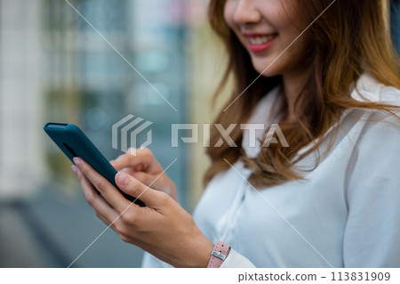 A woman texting on her smartphone while enjoying some leisure time indoors. The portable device allows her to stay connected and entertained with the latest digital information and entertainment. 113831909
