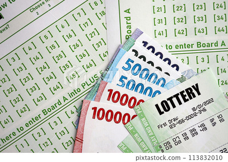 Green lottery tickets and indonesian money bills on blank with numbers for playing lottery close up Green lottery tickets and indonesian money bills on blank with numbers for playing lottery close up 113832010
