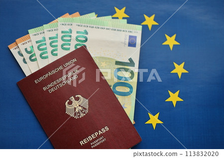 Red German passport of European Union and money on blue flag background close up. Tourism and citizenship concept 113832020