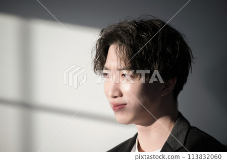 A young man dazzled by the light coming through the window 113832060